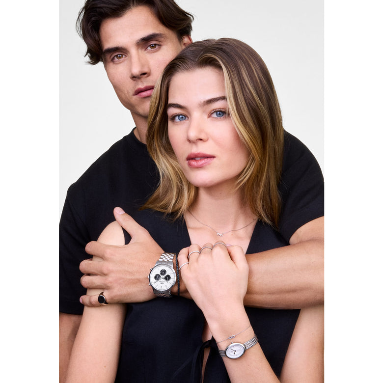 Woman wearing the Mirelle Infinity Bracelet Silver with a sparkling infinity charm and fine chain, styled alongside a silver watch and layered jewellery for a modern, everyday look.