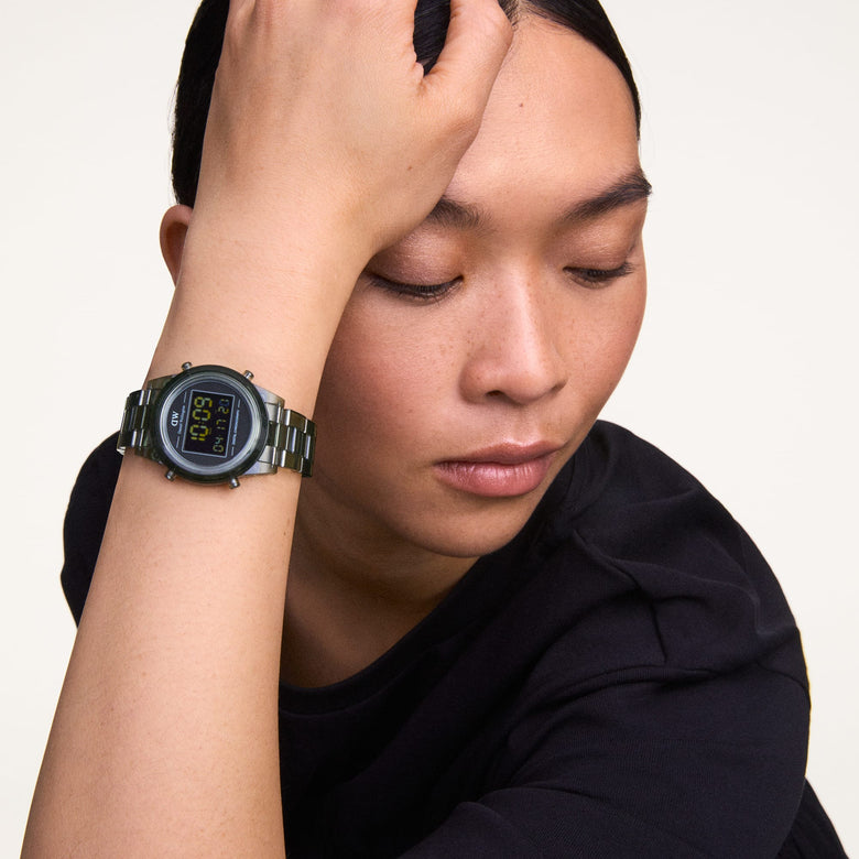 A person wearing the Retro Digital Dark Green watch with a transparent dark green strap and round black digital dial, styled casually with a short sleeve black top.