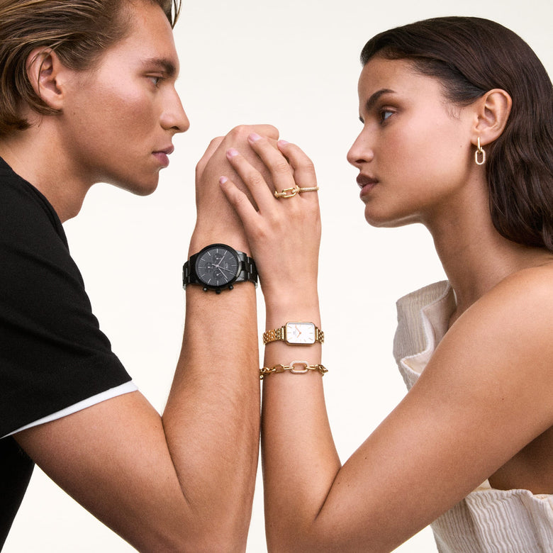 A woman wearing the Quadro 5-Link Evergold watch with a gold rectangular case and white dial, styled alongside gold jewellery, in a casual social setting.