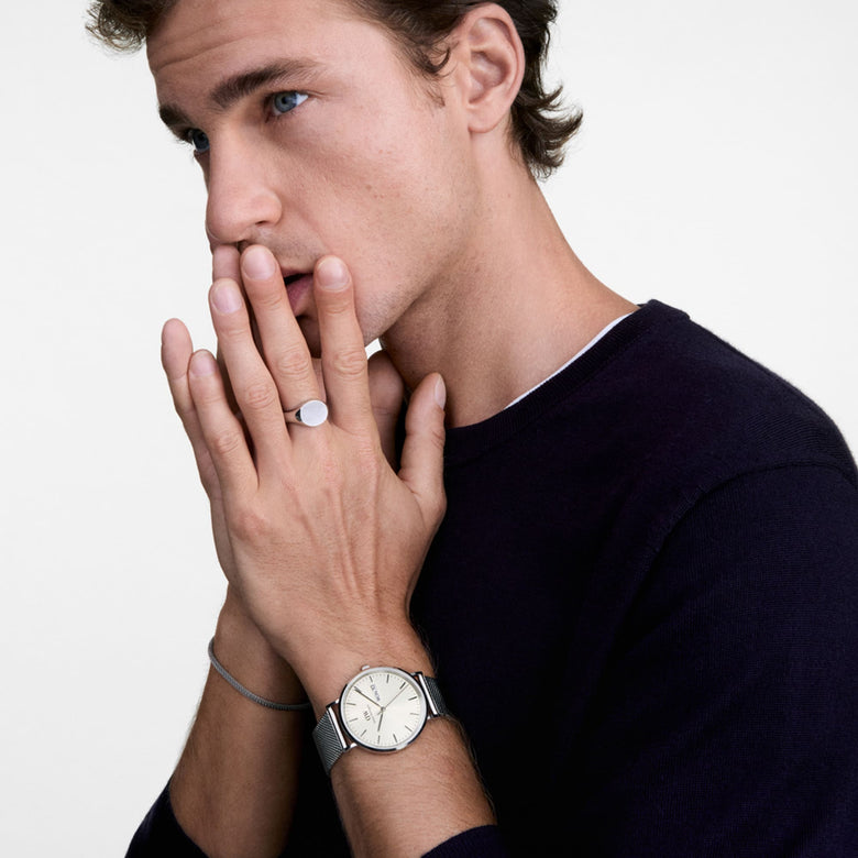 A man wearing the Classic Day Display Sterling Champagne watch with a silver mesh strap and champagne dial, styled with a dark jumper for a modern, understated look suitable for everyday wear.