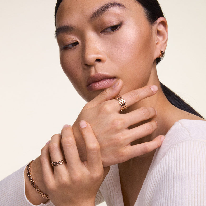 Woman wearing the 3-Link Ring Rose Gold, styled with matching rose gold bracelet and earrings, showcasing the ring's geometric chain link design and polished finish for an elegant, modern look.