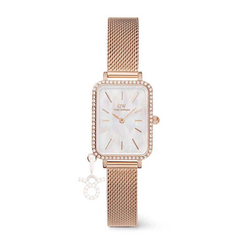 Rose gold ladies watch with a rectangular case, white mother of pearl dial, crystal border, and an interchangeable zodiac charm on an adjustable mesh strap.