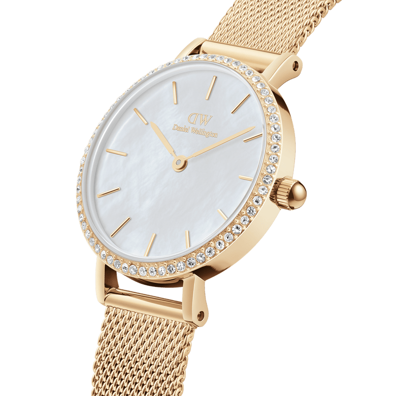 Close-up of the Petite Lumine Bezel Evergold MOP gold watch, featuring a white mother of pearl dial, gemstone bezel, and an adjustable gold mesh strap, highlighting its elegant and refined details.