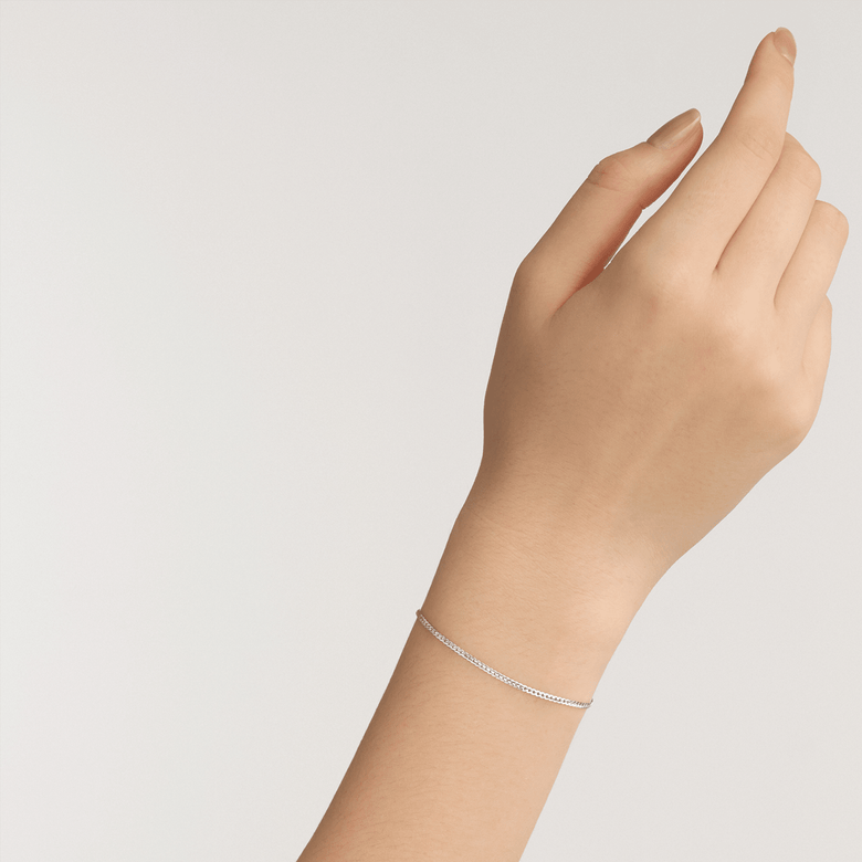 A woman’s wrist wearing the Flat Chain Bracelet S, showcasing its slim silver chain and minimalist design for a refined, everyday look.