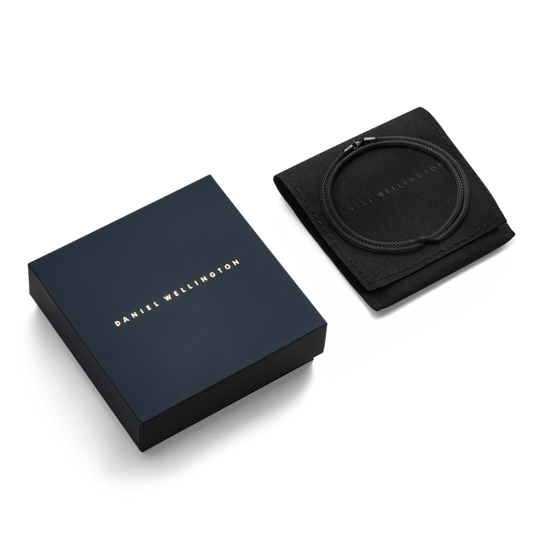 Tide Mesh Necklace Black 2.8 presented coiled on a black pouch next to a Daniel Wellington gift box, highlighting its elegant packaging for gifting or personal use.