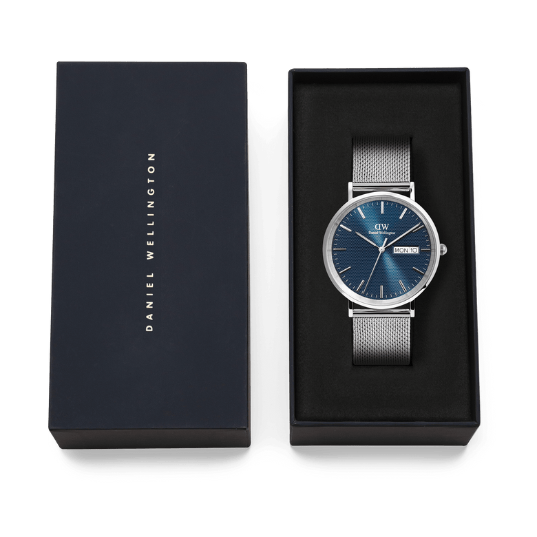 Classic Day Display Sterling Arctic men's watch with a blue patterned dial and stainless steel mesh strap, presented in a Daniel Wellington branded gift box.