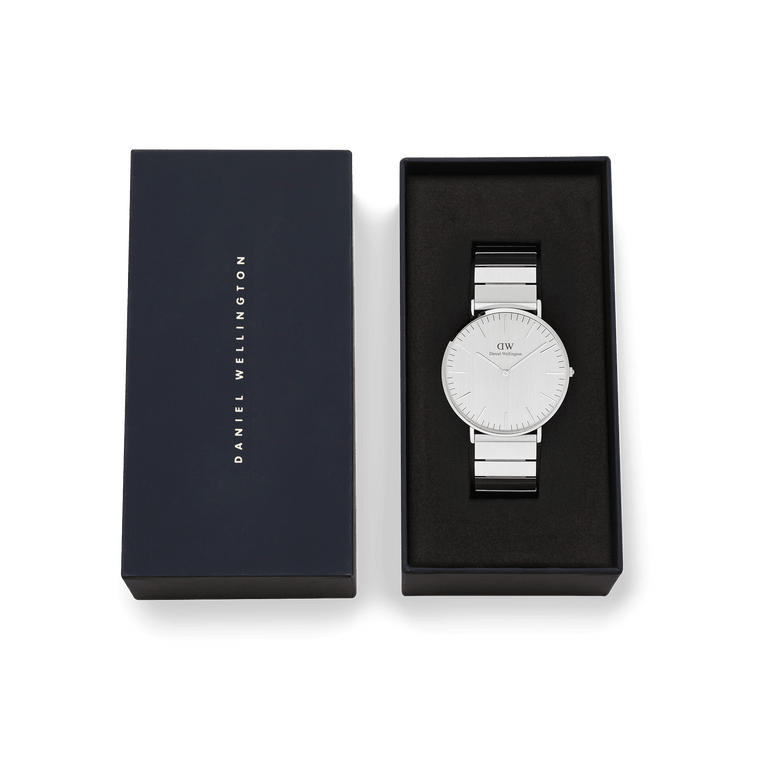 Classic Piano Link Silver Unitone men's watch with a brushed silver dial and stainless steel bracelet, presented in a sleek black Daniel Wellington gift box.