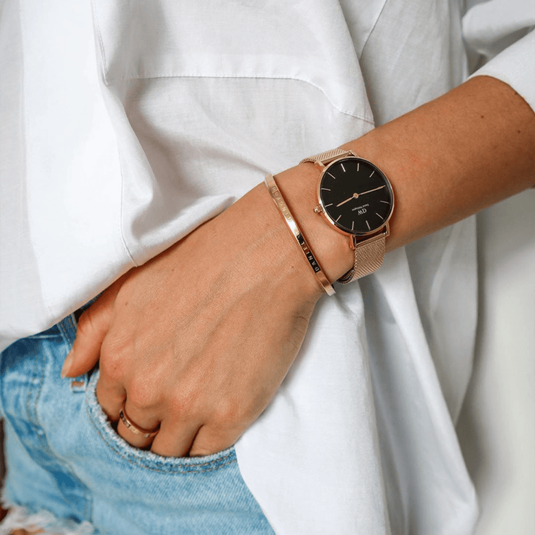 Petite Evergold Black gold mesh strap watch worn on a woman's wrist, styled with a gold bangle and casual denim and white shirt, highlighting its elegant and versatile design for everyday wear.