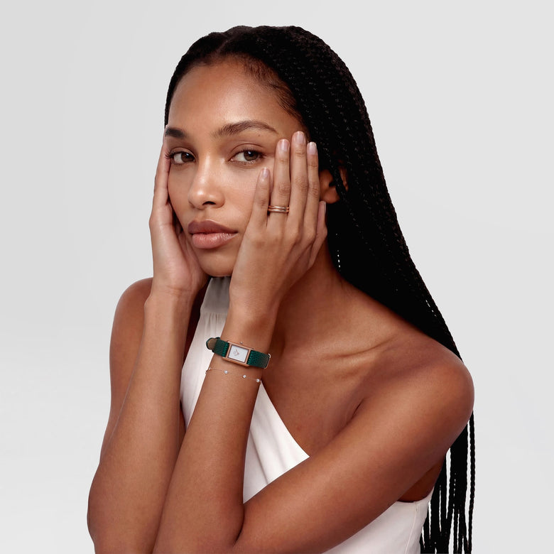 A woman wearing the Bound Mini Green Lizard Rose Gold watch, featuring a slim rectangular rose gold case and textured green lizard leather strap, styled with a minimalist white dial and paired with a delicate bracelet.