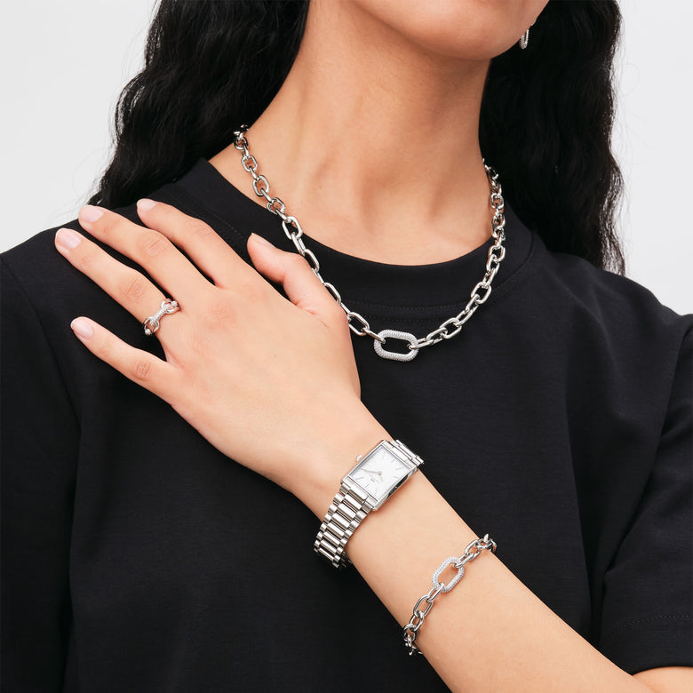 Woman wearing the Crystal Link Ring Silver on her finger, styled with matching chain link necklace and bracelet, and a silver watch, showcasing a coordinated modern jewellery look.