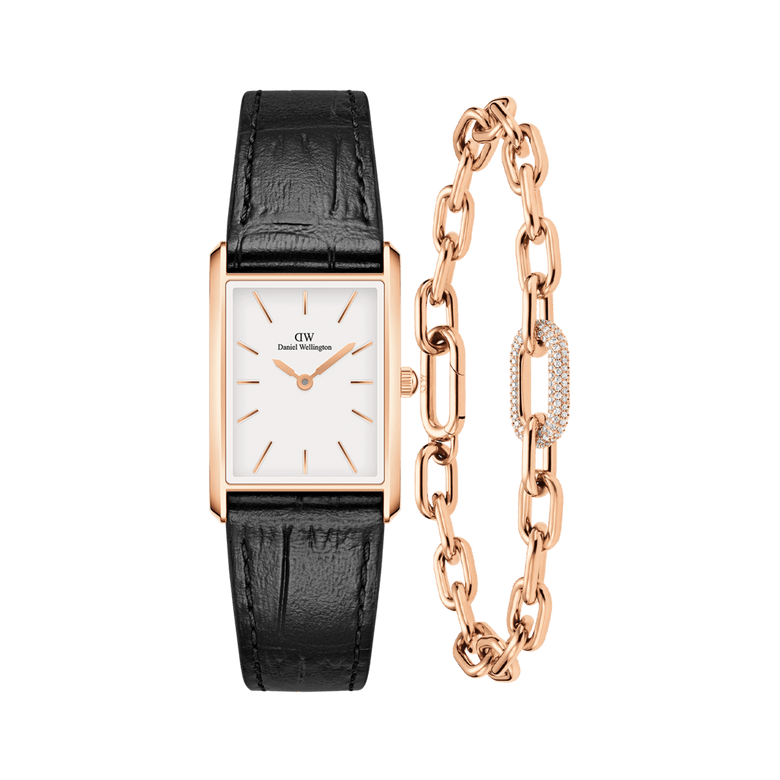 Rectangular rose gold watch with a white dial and black crocodile-embossed leather strap, paired with a rose gold crystal link bracelet featuring a pavé crystal accent and delicate chain.