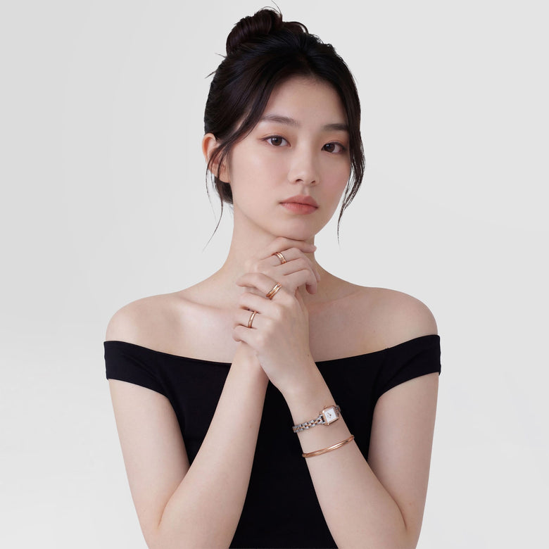 A woman wearing the Quadro Mini Arch 3-Link Two Tone Rose Gold ladies watch, styled with matching rose gold jewellery and a black off-shoulder top, highlighting the watch’s petite rectangular case and elegant two tone bracelet.