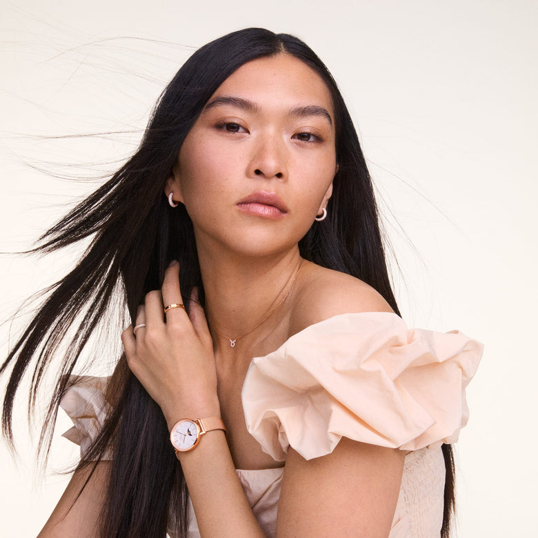 Woman wearing Pavé Crystal Earrings Rose Gold, styled with a rose gold watch and delicate jewellery, showcasing the petite hoop earrings and their sparkling pavé crystal setting against a soft, neutral outfit.