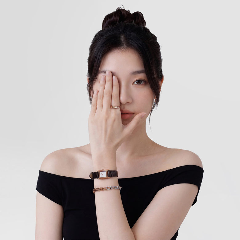 Woman wearing the Bound Mini Dark Brown Lizard Rose Gold watch, featuring a slim brown lizard-grain leather strap and rectangular rose gold case, styled with a rose gold and silver bracelet for a modern, elegant look.