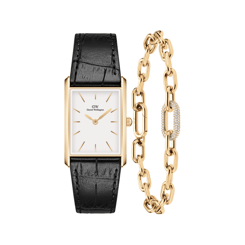 Rectangular gold watch with a white dial and black crocodile-embossed leather strap, paired with a gold chain-link bracelet featuring a pavé crystal accent and polished finish.