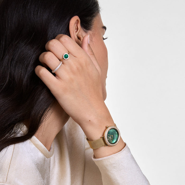 A woman wearing the Pavé Crystal Ring Silver Set, showcasing two slim silver rings with pavé-set crystals stacked together, styled alongside a gold watch and an emerald ring for a modern, elegant look.