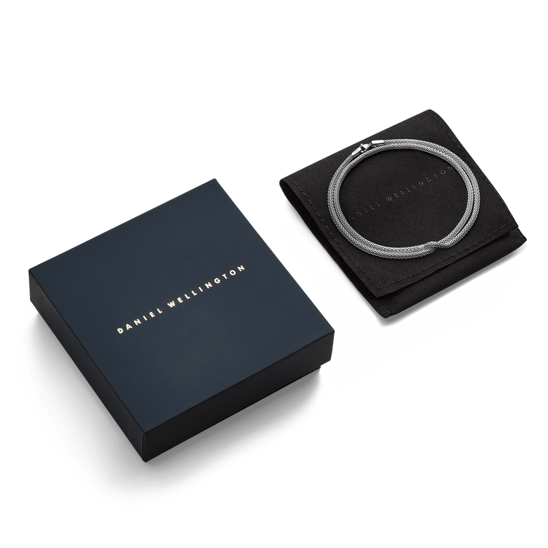 Tide Mesh Necklace Silver 2.8 displayed coiled on a black pouch next to a navy Daniel Wellington gift box, highlighting its polished silver mesh chain and elegant presentation for gifting.