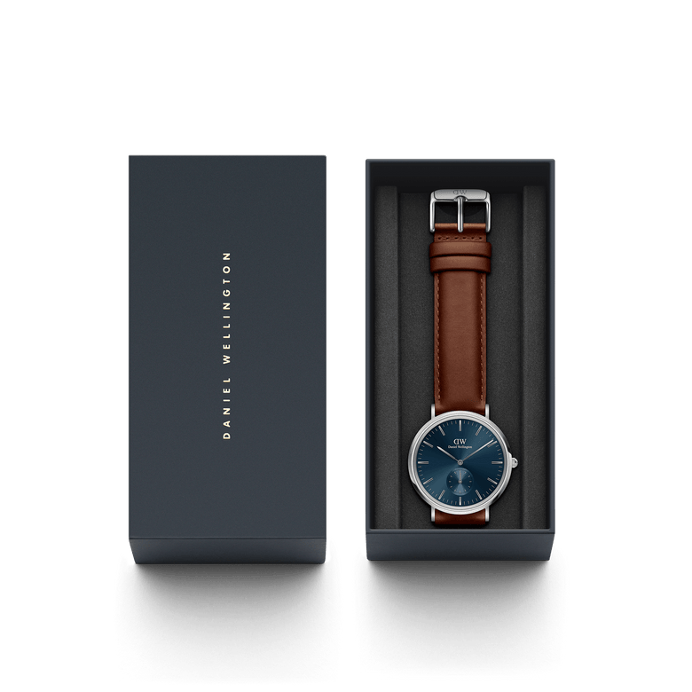Classic Multi-Eye St Mawes Arctic Silver men's watch with a deep blue dial and brown leather strap, presented in a branded Daniel Wellington gift box.