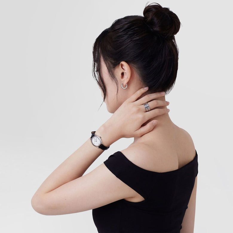 A woman wearing the Line Earring Brushed Silver 3.5mm, styled with her hair up and paired with a silver ring and a classic watch, highlighting the minimalist silver hoop earring's subtle brushed finish and modern look.