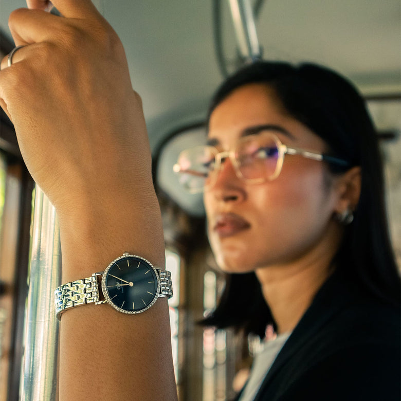 Petite Lumine Bezel 5-Link Arctic S silver watch with a deep blue dial and crystal bezel, worn on a woman's wrist in a casual urban setting.