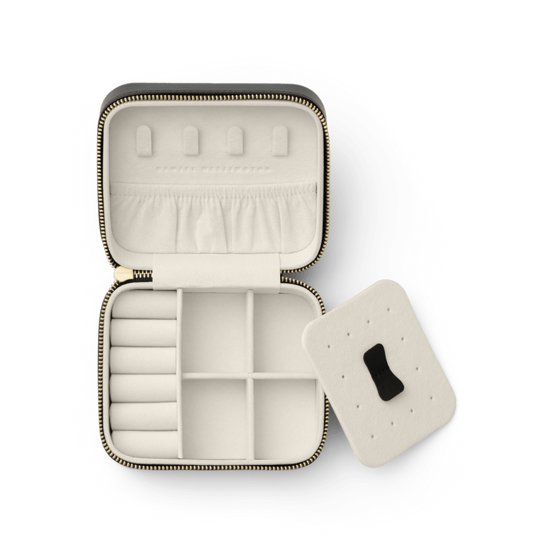 Travel Jewellery Box Black by Daniel Wellington with a gold zip, open to show soft cream lining, multiple compartments, ring holders, pouch pocket, and a removable divider for organised accessory storage.