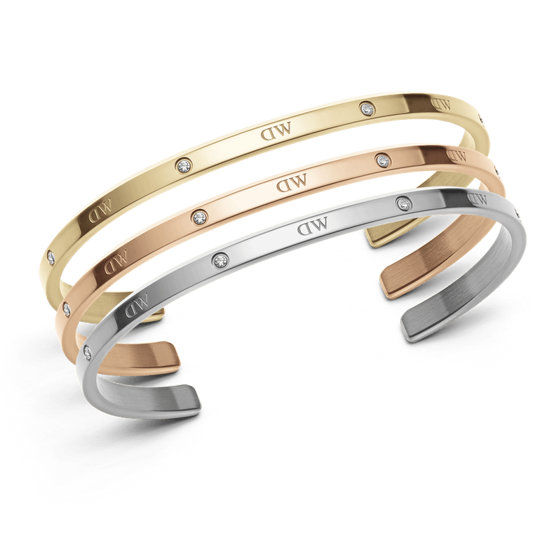 Three slim cuff bracelets in rose gold, silver, and gold tones with sparkling crystal accents and engraved detail, displayed together to highlight their elegant, minimalist design and versatility for layering.