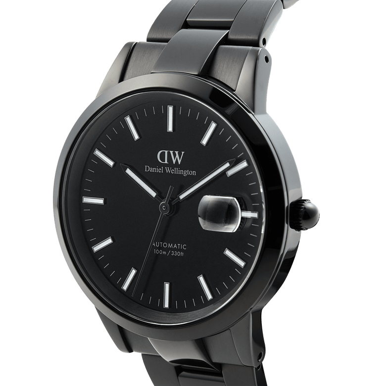 Close-up of the Daniel Wellington Iconic Link Automatic Black watch, highlighting its black stainless steel bracelet, luminous black enamel dial, and magnified date display.