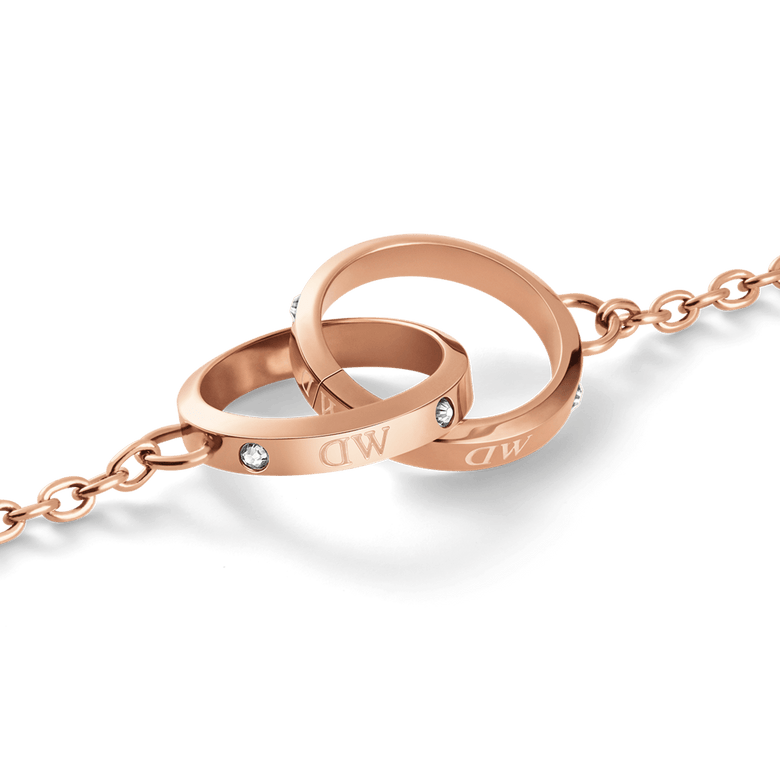 Close-up of the Classic Unity Lumine bracelet pendant, showing two intertwined rose gold rings with sparkling crystal accents and delicate chain detailing.