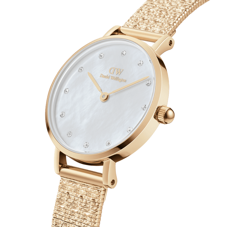 Petite Lumine Pressed Piano White MoP Gold watch with a cloud-textured gold Studio Strap, white mother of pearl dial, and crystal hour markers, shown in a close-up angle highlighting its slim and elegant profile.