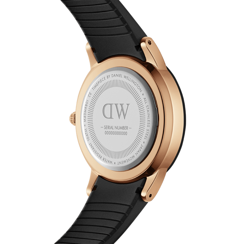 Back view of the Daniel Wellington Iconic Motion Rose Gold watch, showing the rose gold stainless steel case, engraved case back, and textured black FKM rubber strap.