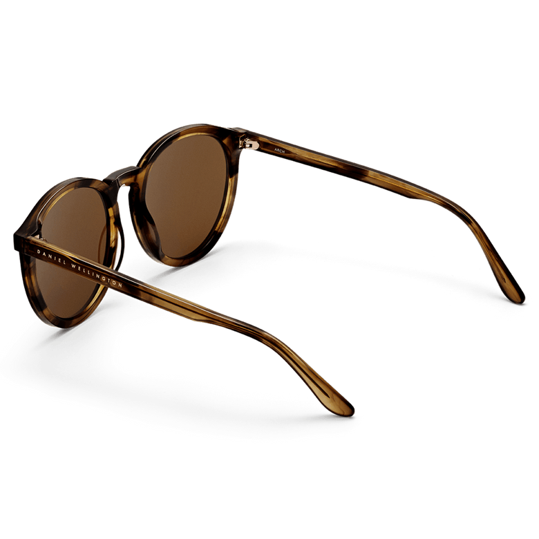 Bio-Acetate Arch Brown Demi sunglasses with round brown demi frames, amber coloured lenses, and Daniel Wellington branding on the temples, shown from the back to highlight the curved arms and smooth finish.