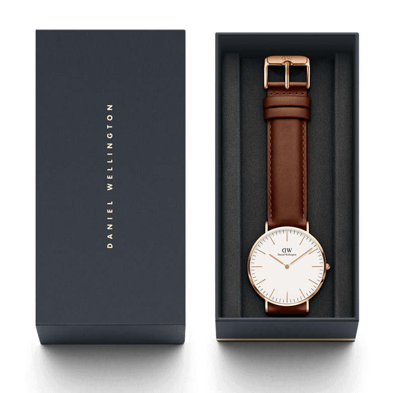 Classic St Mawes Rose Gold watch with a brown leather strap and minimalist white dial, elegantly presented in a Daniel Wellington gift box.