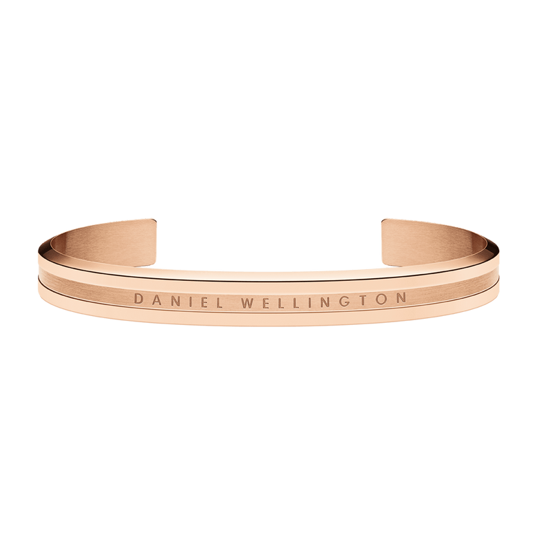 Elan Bracelet Rose Gold by Daniel Wellington with a polished rose gold finish, minimalist open cuff design, and engraved logo, crafted from stainless steel and suitable for layering with other jewellery.