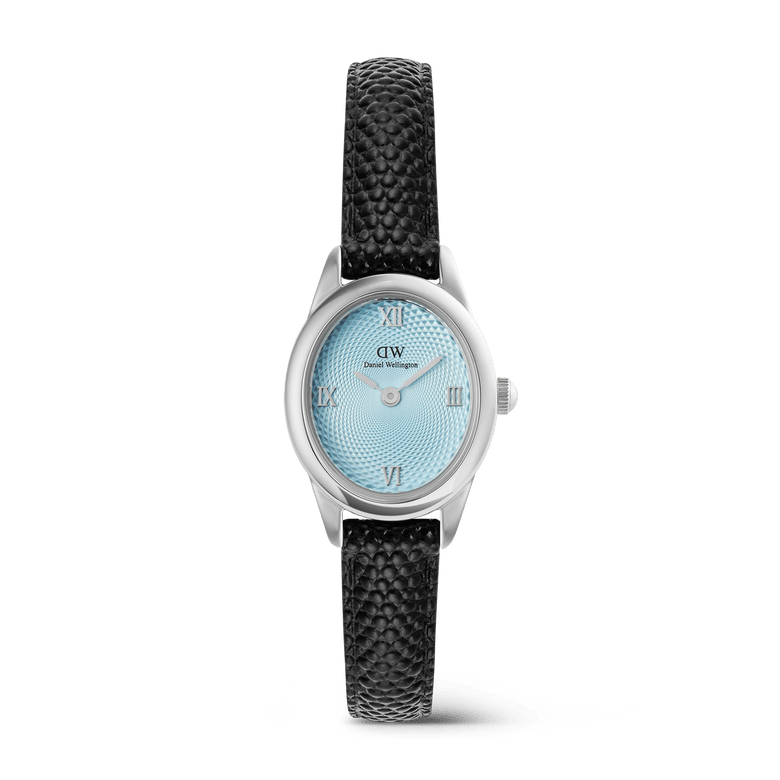 A petite women’s watch featuring an oval silver case, ice blue guilloché dial with silver Roman numerals, and a textured black lizard-embossed leather strap.