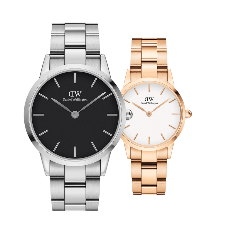 Two Daniel Wellington Iconic Link watches displayed side by side, featuring a silver watch with a black dial and a rose gold ladies watch with a white dial, both with steel link straps and minimalist design.