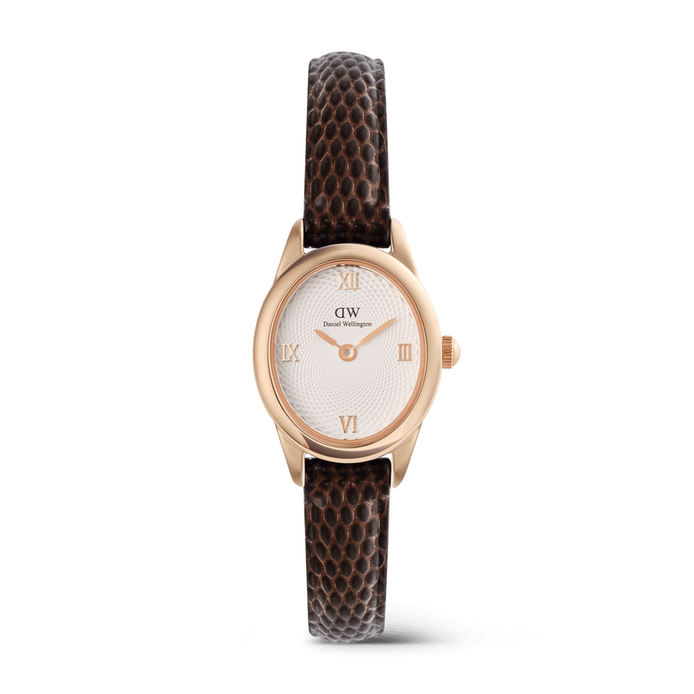 Ladies rose gold watch with a petite oval case, white guilloché dial, Roman numeral markers, and a dark brown lizard-embossed leather strap, blending classic elegance with modern style.