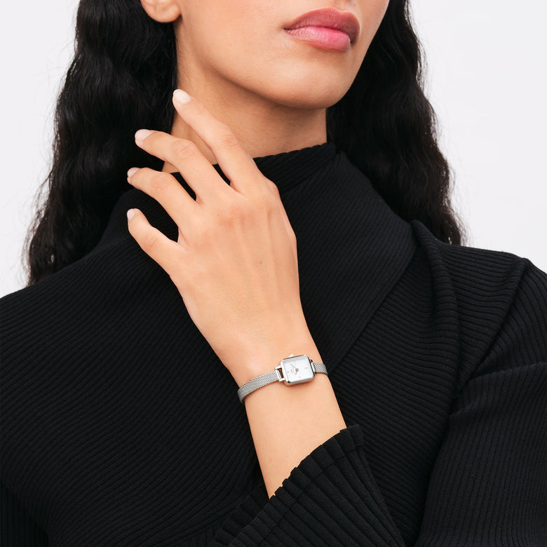 A woman wearing the Quadro Mini Sterling silver ladies watch with a petite rectangular case and slim mesh strap, styled elegantly with a black ribbed top.