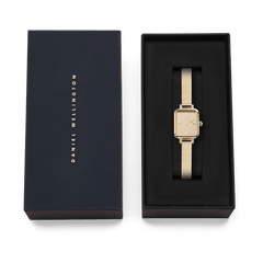 Quadro Mini Reflection Gold presented in a sleek black Daniel Wellington gift box, highlighting its slim rectangular gold case and elegant mesh strap, ideal for gifting or adding to your collection.