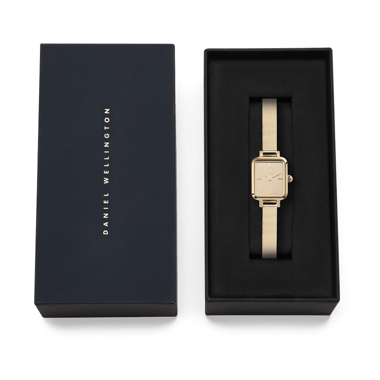 Quadro Mini Reflection Gold presented in a sleek black Daniel Wellington gift box, highlighting its slim rectangular gold case and elegant mesh strap, ideal for gifting or adding to your collection.