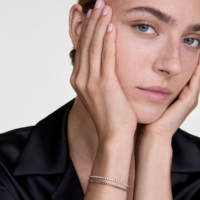 A woman wearing the Classic Tennis Bracelet Honey Combo Silver, featuring alternating honey and clear crystals on a slim silver chain, styled elegantly with a black shirt for a refined, minimalist look.