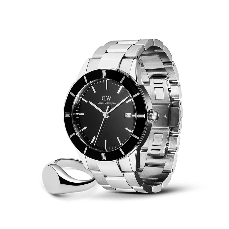 Silver stainless steel Daniel Wellington watch with a black dial and silver hour markers, paired with a polished silver signet ring featuring a sleek black face, both styled for men seeking modern elegance and versatility.