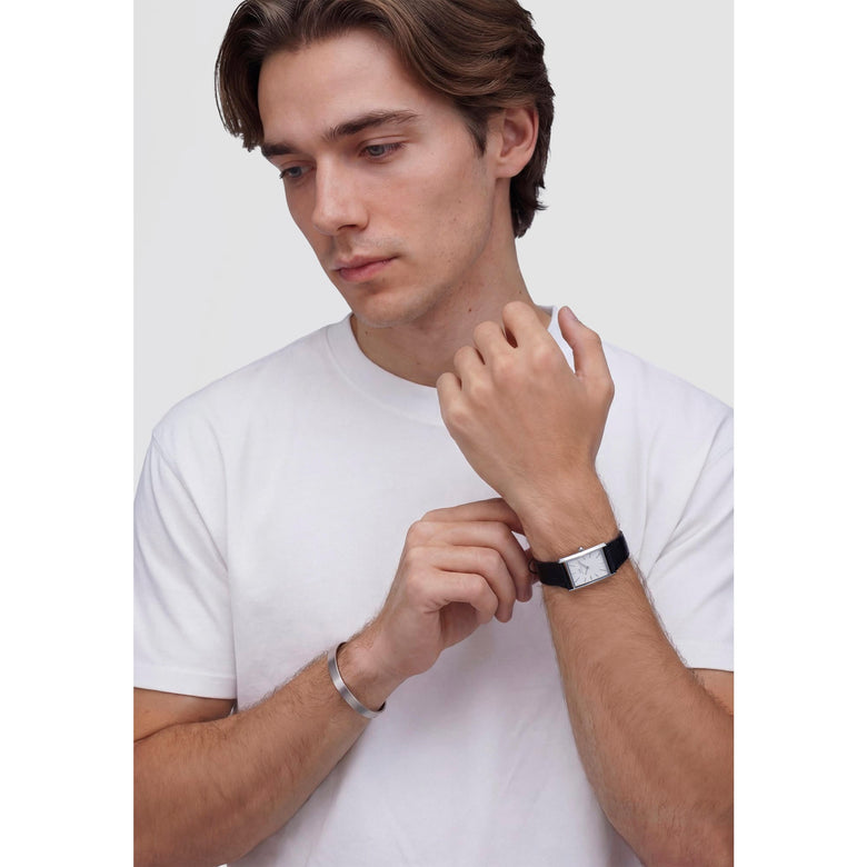 A person wearing the Bound Black Crocodile Guilloché Silver watch, showing its rectangular silver case, white textured dial, and black crocodile-embossed leather strap styled with a casual white T-shirt.