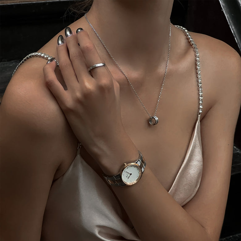 Woman wearing the Iconic Link Lumine Rose Gold watch with a two-tone rose gold and silver bracelet, eggshell white dial, and crystal hour markers, styled with silver jewellery and a satin dress for an elegant evening look.