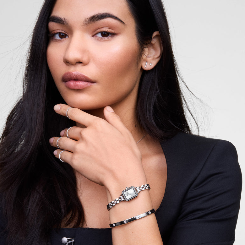 A woman wearing the Classic Lumine Bracelet Silver 5.5mm, styled alongside a silver watch and minimalist rings, showcasing the bracelet’s polished silver finish and sparkling crystal accents for a refined, modern look.