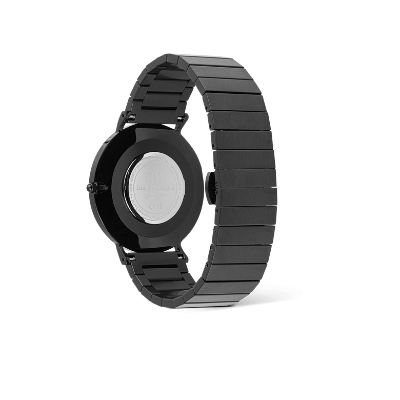 Classic Piano Link Onyx Unitone Black watch by Daniel Wellington viewed from the back, showing the brushed stainless steel piano link bracelet and engraved case back.