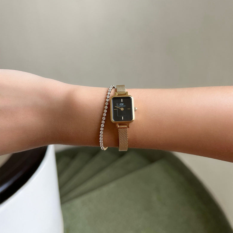 Quadro Mini Evergold Onyx gold watch with a rectangular black dial and gold mesh strap, worn alongside a delicate diamond bracelet for a sophisticated, jewellery-inspired look suitable for petite wrists.