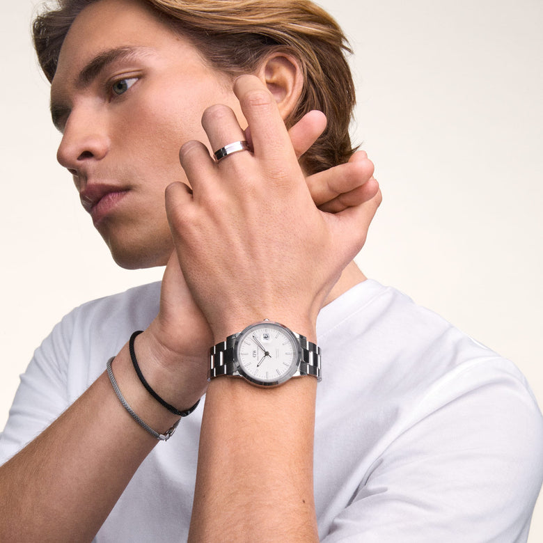 A man wearing the Daniel Wellington Iconic Link Automatic Silver watch, featuring a polished stainless steel bracelet and minimalist white dial, styled with casual jewellery and a white T-shirt for a modern everyday look.