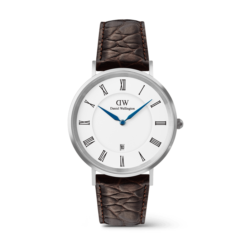 Classic men’s watch with a silver stainless steel case, white dial featuring Roman numerals, blue hands, date display, and a dark brown crocodile-embossed leather strap.