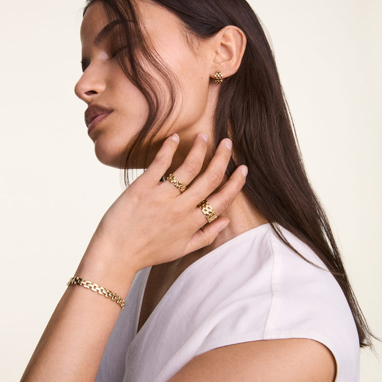 Woman wearing the 3-Link Bracelet Gold on her wrist, styled with matching gold rings and earrings, showcasing the bracelet’s geometric link design and polished finish for a modern, elegant look.