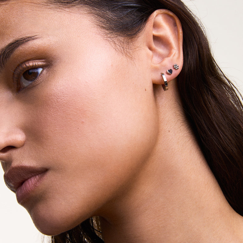 Hoop Earring Silver worn on the ear, showcasing its petite size and polished stainless steel finish, styled with other small earrings for a modern and versatile look suitable for everyday wear.